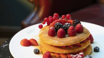 A stack of pancakes topped with berries and syrup.