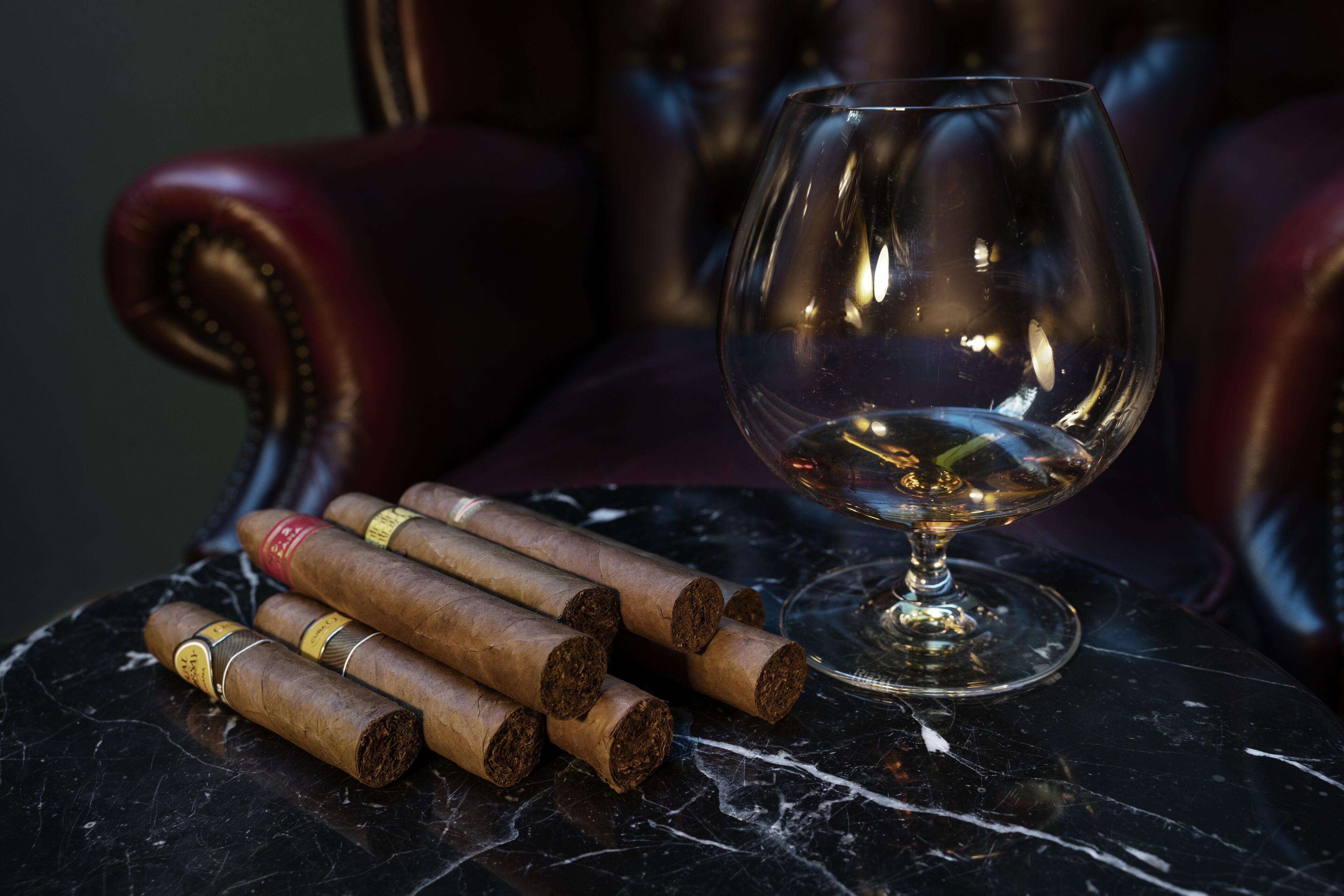 A table with cigars and an empty glass on a marble surface.