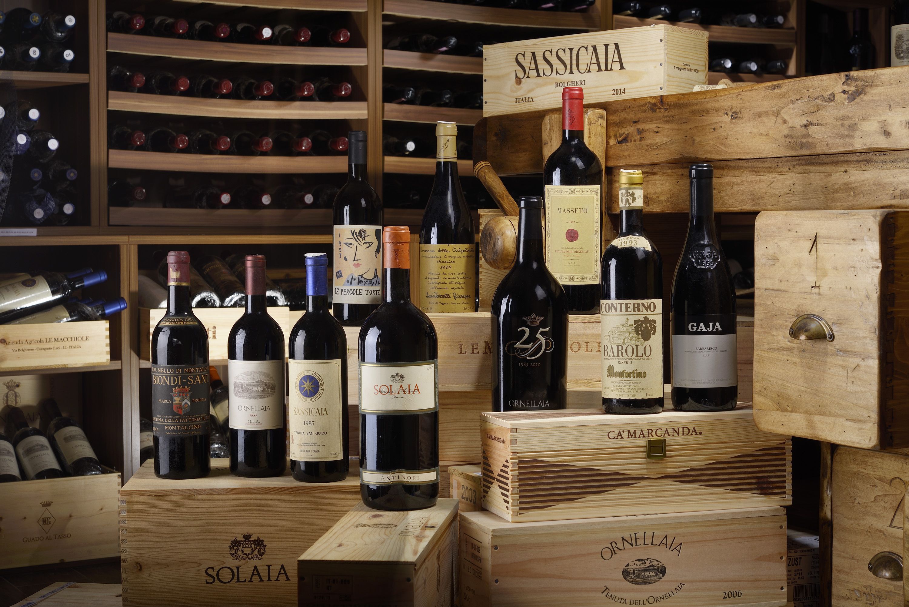 Une cave à vin avec des caisses en bois et des bouteilles de vin, notamment des marques comme Solaiia et Cassicata.