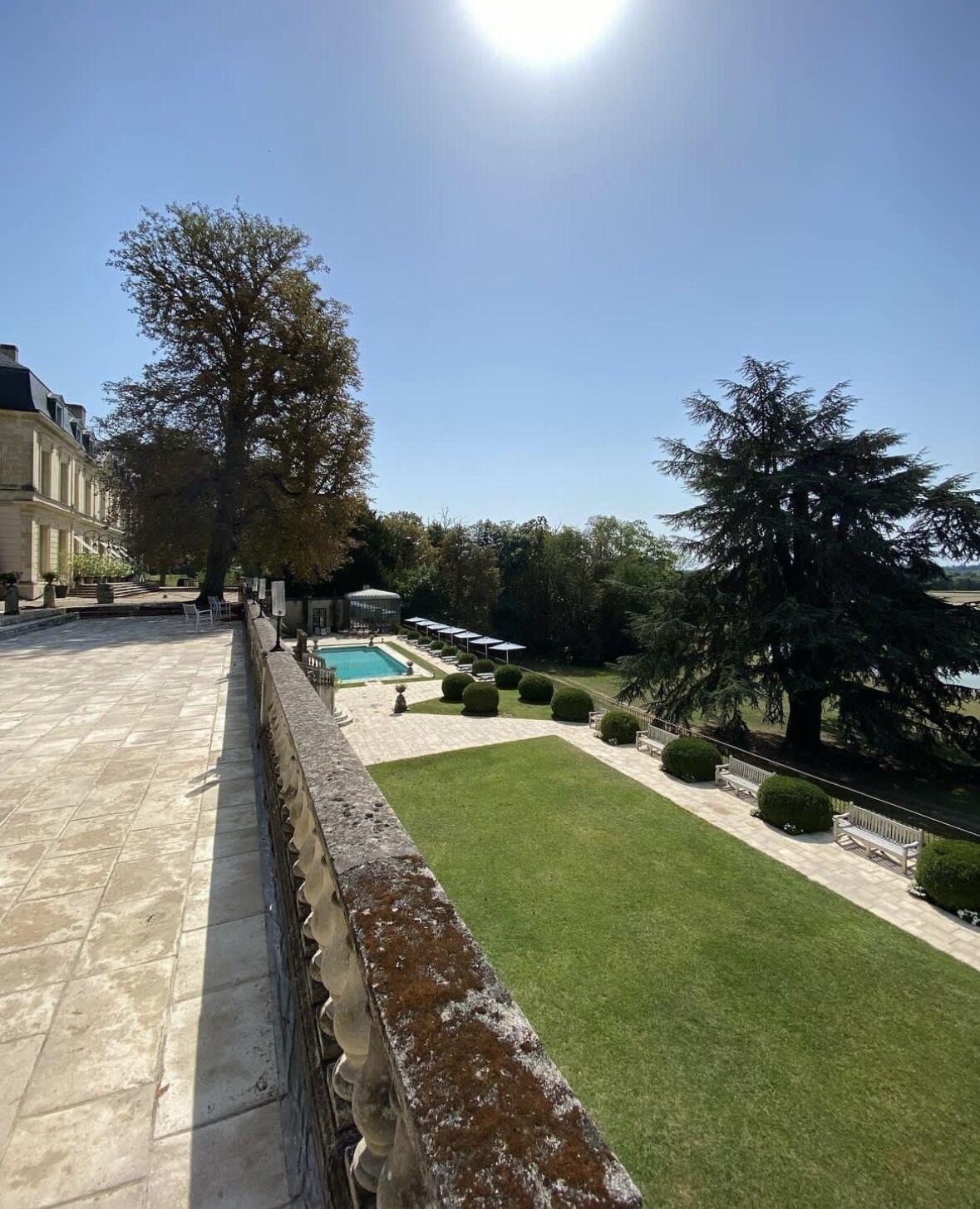 Une cour avec une piscine, une pelouse et un mur en pierre.