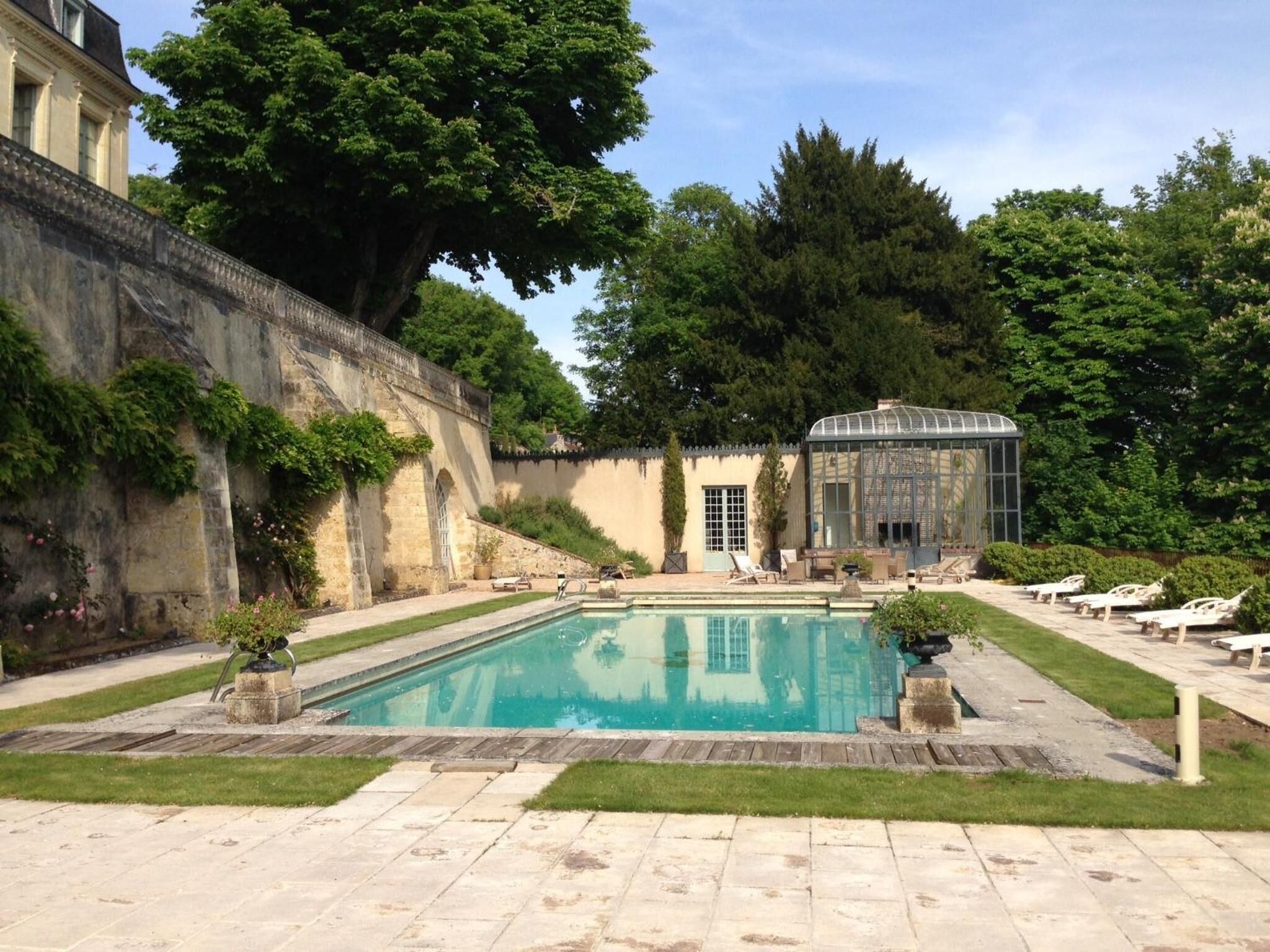 Ein Schwimmbad mit Liegestühlen und einem Wintergarten.