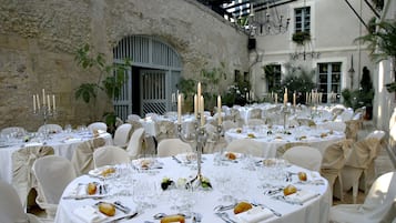 Une salle de banquet avec des tables rondes dressées pour un événement formel, agrémentée de nappes blanches, de bougies et de décorations de table élégantes.