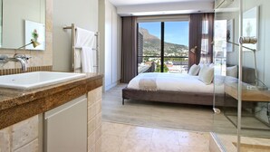 Habitación de hotel moderna con una cama grande, cabina de ducha de vidrio, baño con lavabo y espejo, y vista a la ciudad.