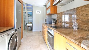 Una cocina moderna con electrodomésticos de acero inoxidable, encimeras de granito y armarios de madera.