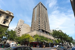 A tall building with multiple floors, a parking area, and a street with cars and pedestrians. - ITC Hospitality Group Three Bedrooms Cartwright s Corner (Cape Town)
