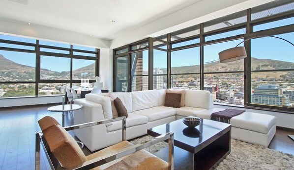 A modern living room with a large window, a white sofa set, and a coffee table.