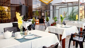 Un restaurant doté d’une terrasse, de tables recouvertes de nappes blanches et agrémenté de plantes en pot.