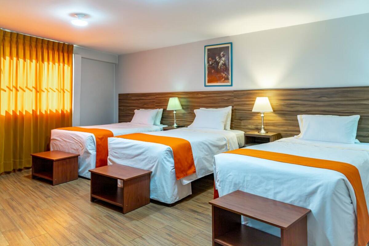 A hotel room with two beds, wooden headboards, bedside tables, and a painting on the wall.