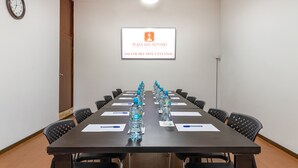 Une salle de conférence avec une longue table, des chaises, des bouteilles d’eau et une horloge au mur.