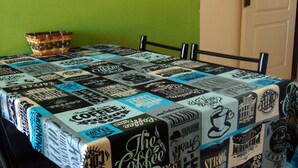 Una mesa cubierta con un mantel con motivos y texto relacionados con el café.