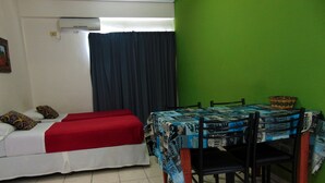 Una habitación con una cama, una mesa con sillas y una pared verde.