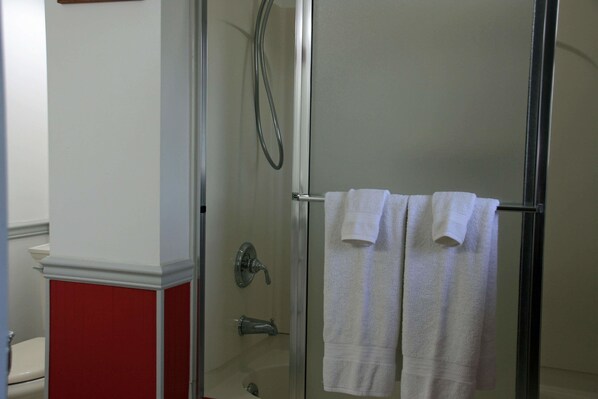 A bathroom with a glass shower enclosure, a toilet, and two towels hanging on a rack. - Carriage Corner Bed & Breakfast (Gordonville)