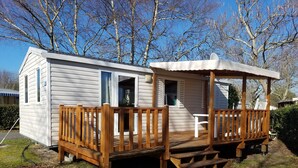 A mobile home with a wooden deck and a covered porch. - Rêve en famille (Gastes)