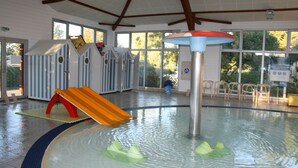 An indoor swimming pool with a slide, play structures, and a ceiling fan. - Rêve en famille (Gastes)