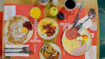Bandeja de desayuno con panqueques, huevos revueltos, tocino, salchicha, queso y pan.