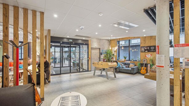 A lobby with a wooden partition, a reception desk, a seating area with a guitar, and a coffee table. - ibis Saint Germain en Laye Centre (Saint-Germain-en-Laye)
