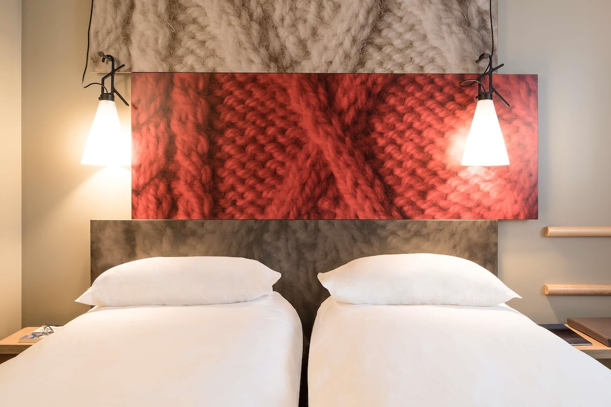 Ein Hotelzimmer mit zwei Betten, einer Marmorwand und Pendelleuchten.