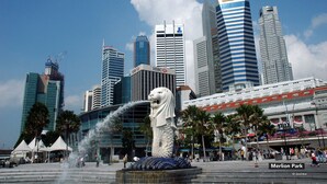 A cityscape with modern skyscrapers, including HSBC and a building with a crane. In the foreground, there's a statue of a lion and a fountain. - ZEN Rooms People's Park Complex (Singapore)