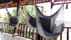 Two hammocks suspended from a wooden ceiling, a concrete floor, and a metal railing. - Hotel con Corazón (Granada)