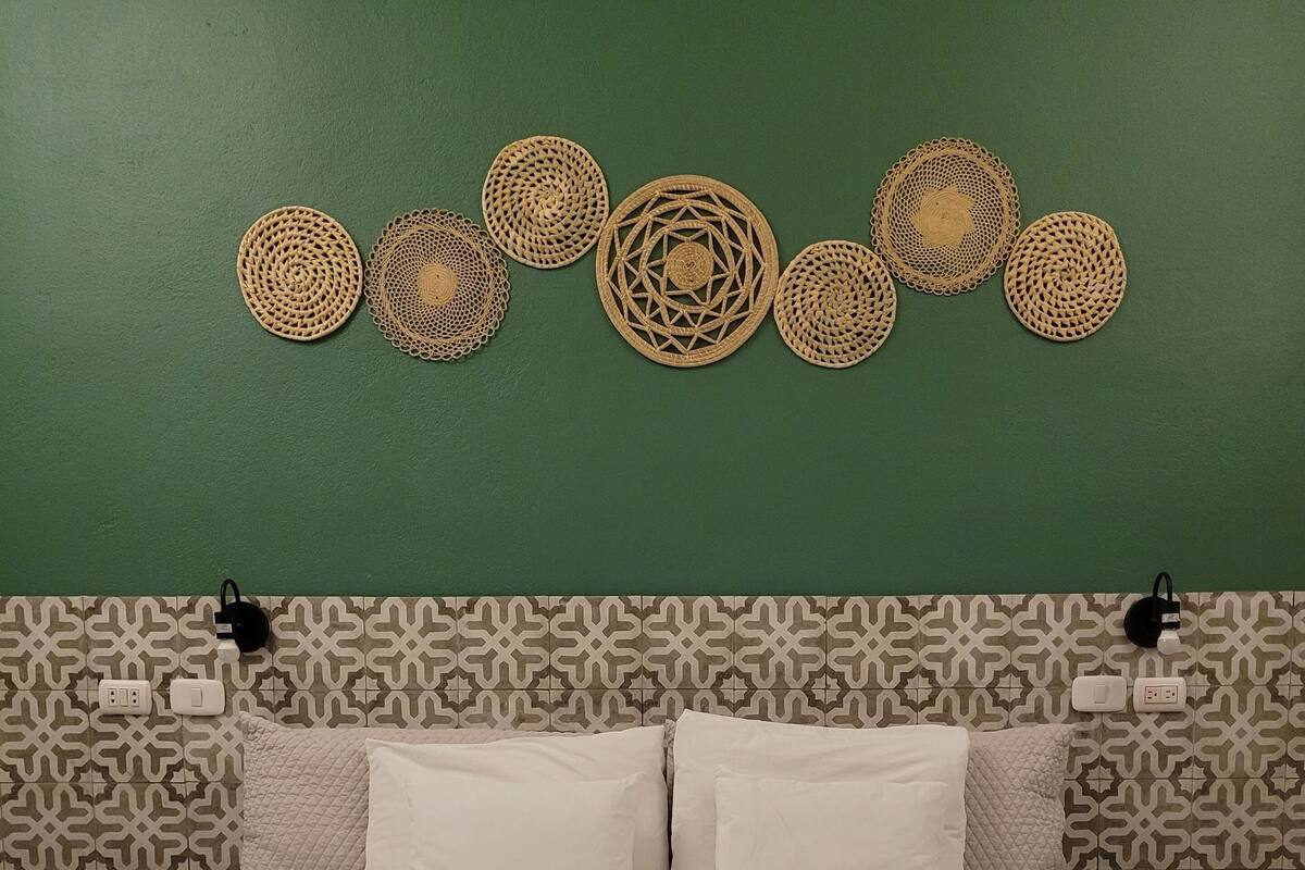 A bed with a white quilted bedspread, two white pillows, and a headboard with a geometric pattern.