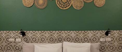 A bed with a white quilted bedspread, two white pillows, and a headboard with a geometric pattern.