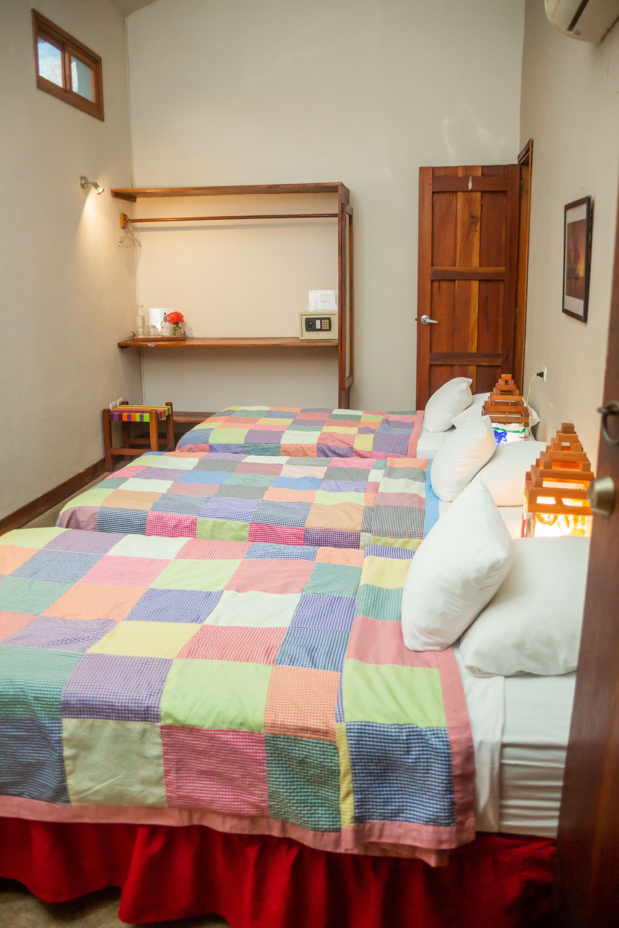 A bedroom with two beds, a wooden shelf, a small chair, and a door.