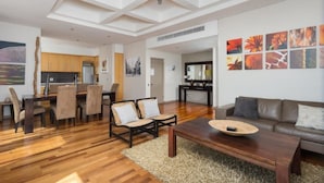 A spacious living area with a wooden floor, a dining set, a sofa, and a coffee table. - ITC Hospitality Group Two Bedrooms Cartwright's Corner (Cape Town)