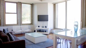 A modern living room with a glass coffee table, white sofas, a flat-screen TV, and large windows. - ITC Hospitality Group Two Bedrooms Cartwright's Corner (Cape Town)