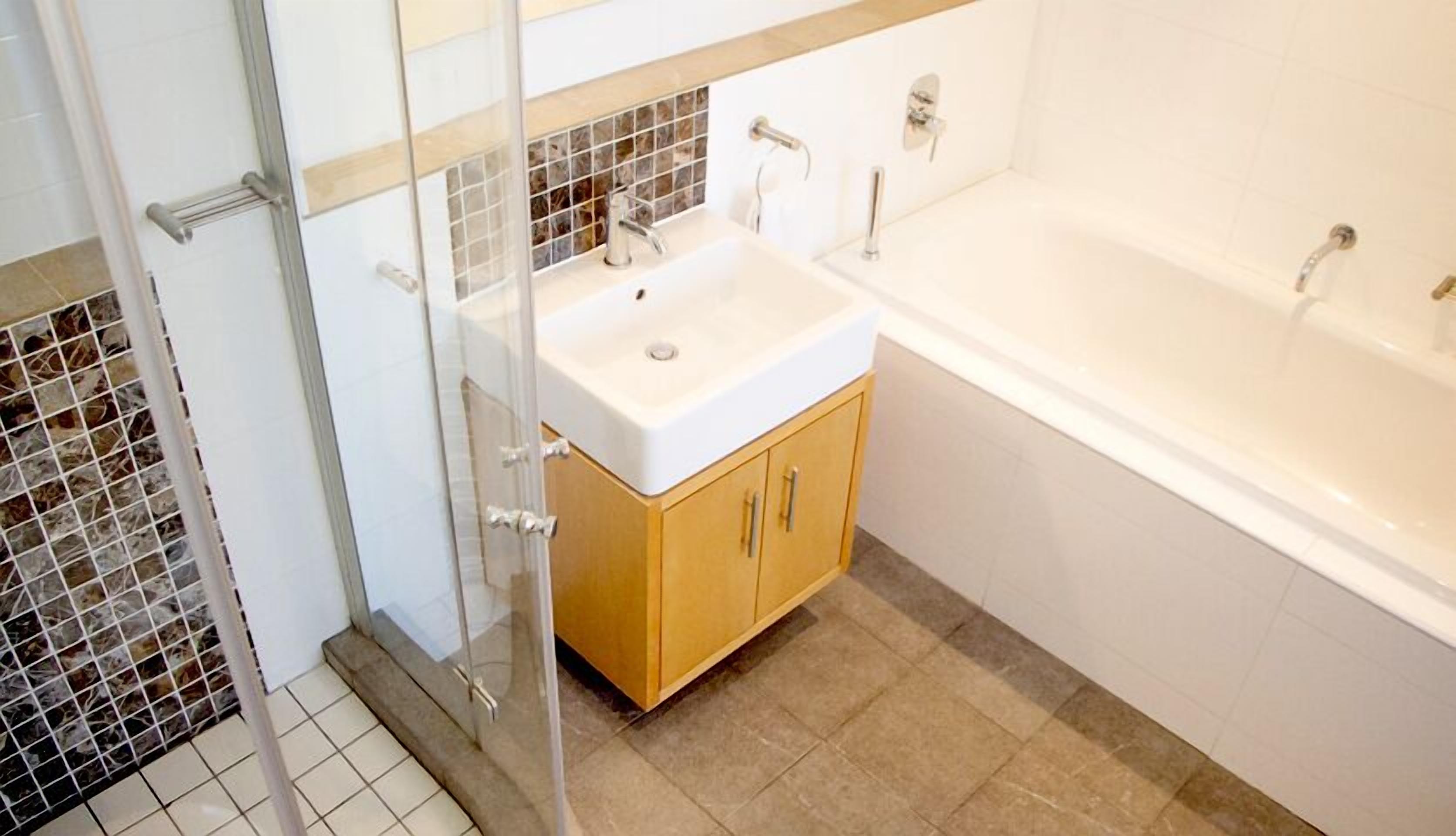 Une salle de bain avec une douche à parois de verre, un lavabo avec un miroir et une baignoire.