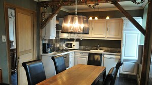 A kitchen with white cabinets, a wooden dining table, and black chairs. - Holiday Home in Hotton near Caves of Hotton (Werpin)