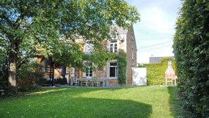 A two-story house with a well-maintained lawn and a large tree in the foreground. - Holiday Home in Hotton near Caves of Hotton (Werpin)