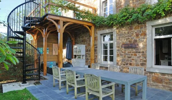 Enjoy al fresco dining under a shaded pergola with a table set for a meal.
