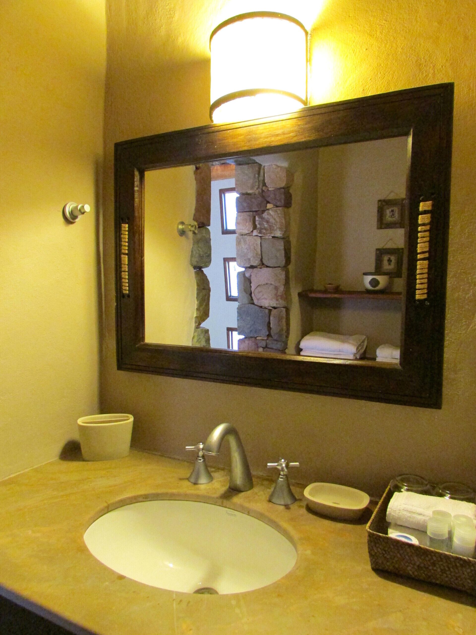 Un baño con lavamanos, espejo y artículos de aseo.