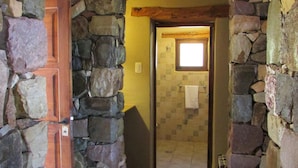 Un corridoio con pareti in pietra, una porta in legno e un lampadario.