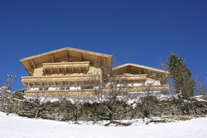 A large wooden building with multiple levels and a sloped roof, surrounded by snow and bare trees. - Chalet in Wald near Zillertal Arena (Wald-Königsleiten)
