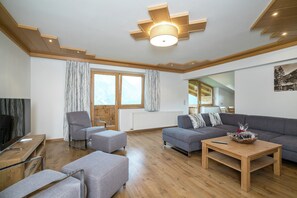 A modern living room with a sofa, armchairs, a coffee table, and a television. - Chalet in Wald near Zillertal Arena (Wald-Königsleiten)