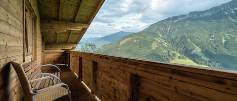 Una cabaña de madera con balcón que da a un paisaje montañoso.