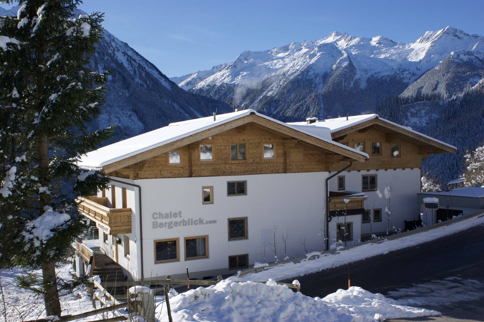 Eine Holzchalet mit Balkon vor einer verschneiten Berglandschaft.