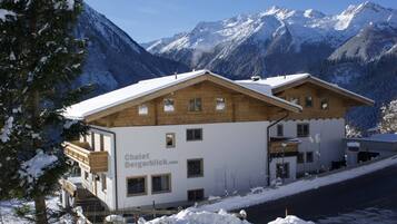 Eine Holzchalet mit Balkon vor einer verschneiten Berglandschaft.