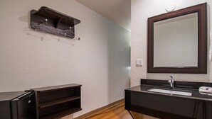 Une salle de bain avec un meuble-lavabo en bois foncé, un miroir et une étagère au-dessus du lavabo.