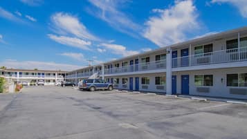 A motel with a two-story structure, a parking lot, and a clear blue sky.