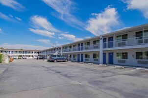 A motel with a two-story structure, a parking lot, and a clear blue sky.
