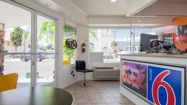 L’intérieur d’un motel, avec une grande fenêtre, une chaise noire, une table et une enseigne publicitaire pour le motel.