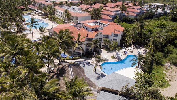 An aerial view of a resort with multiple buildings, a large swimming pool, and palm trees. - Kitewind Apartahotel Cabarete (Cabarete)