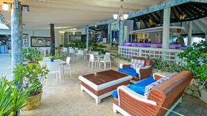 An outdoor lounge area with wicker furniture, a bar, and dining tables. - Kitewind Apartahotel Cabarete (Cabarete)