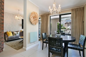 Enjoy city views from the large window in this stylish living space, featuring a dining table, sofa, and flat-screen TV.