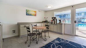 A kitchen with a dining table and chairs, a coffee machine, and a view of a pool through a glass door. - Travelodge by Wyndham Florence (Florence)