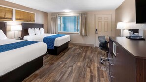 A hotel room with two beds, a desk, a chair, a TV, and a window with curtains. - Travelodge by Wyndham Florence (Florence)