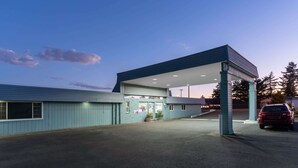 A gas station with a blue exterior, a covered parking area, and a red car parked inside. - Travelodge by Wyndham Florence (Florence)