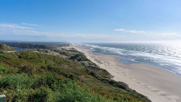 A coastal landscape with a beach, ocean, and hilly terrain. - Travelodge by Wyndham Florence (Florence)